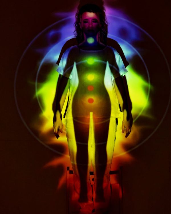 Woman in a balanced yoga pose against a dark background with a warm light accent.